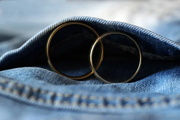 Zwei goldene Eheringe an blauen Jeans. das Konzept der Liebe oder Ehe. — Stockfoto