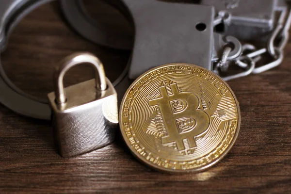 Altın bitcoin, metal kilit ve kelepçe ahşap bir masa, siber suç.