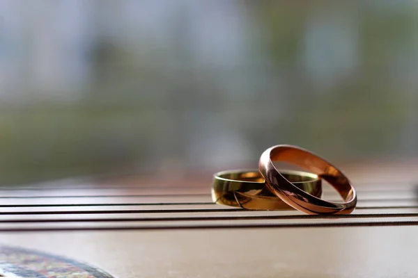 Dua cincin emas pernikahan terletak pada string gitar close-up — Stok Foto