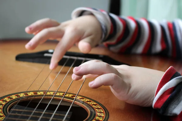 Kytara v rukách dítěte malé holčičky hrající hudbu. — Stock fotografie