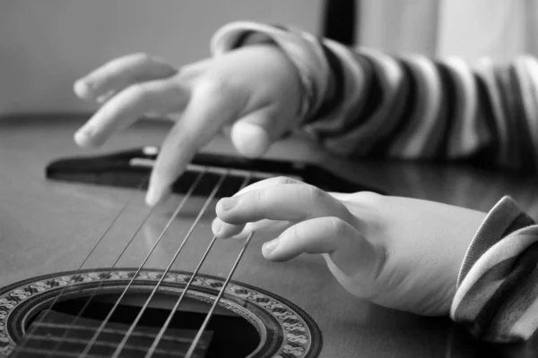Kytara v rukách dítěte malého chlapce, který hraje hudbu. Černobílá — Stock fotografie