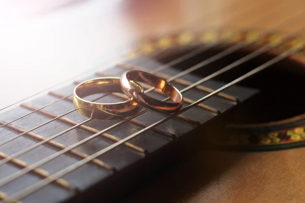 Dois anéis de casamento de ouro mentira em cordas de guitarra close-up — Fotografia de Stock