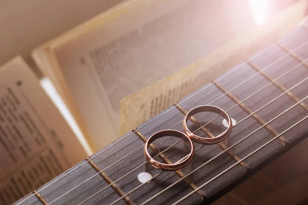 Dois anéis de casamento de ouro mentira em cordas de guitarra close-up — Fotografia de Stock