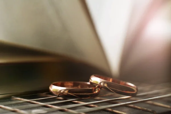 Dois anéis de casamento de ouro mentira em cordas de guitarra close-up — Fotografia de Stock