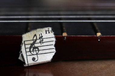Gitar telleri ve yırtık kağıt notalar çok yakın.