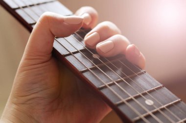 Kadın eli ve gitar telleri, gün batımı.