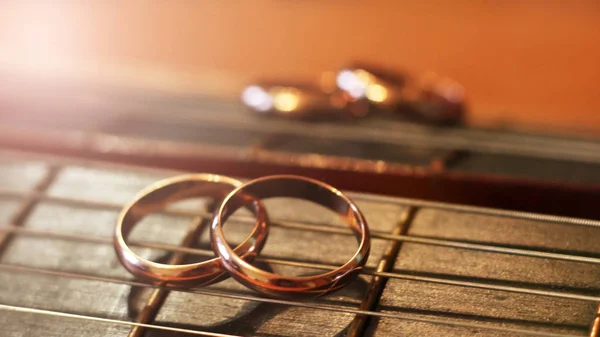 Anéis de casamento nas cordas da guitarra — Fotografia de Stock