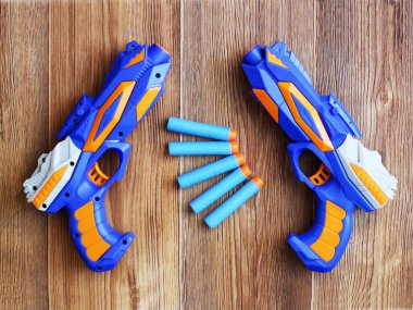 Ahşap arka planda mavi tabanca ve fişekler, bir çocuk için oyuncak.