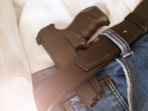 A gun tucked into a leather belt so close