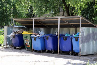 Çöpe atılmış karton kutularla dolu çöp kutuları.