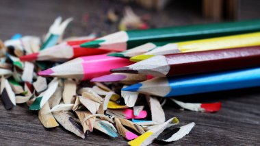 Keskinleştirilmiş kalemler, tahta talaşı, ahşap arka plan.