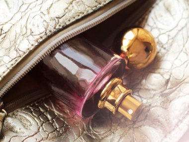 Gri bir çantada pembe parfüm şişesi