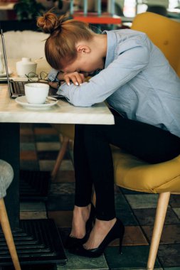 Kızıl saçlı kız bir kafede. Kahve içiyor. Bilgisayar kontrol raporları.