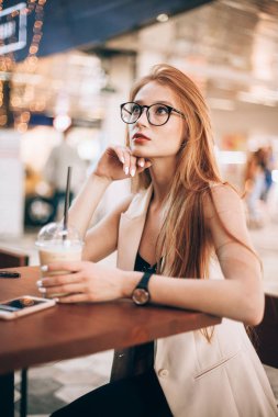 Bir kafede oturan Kızıl saçlı kız. Sütlü kahve içme.