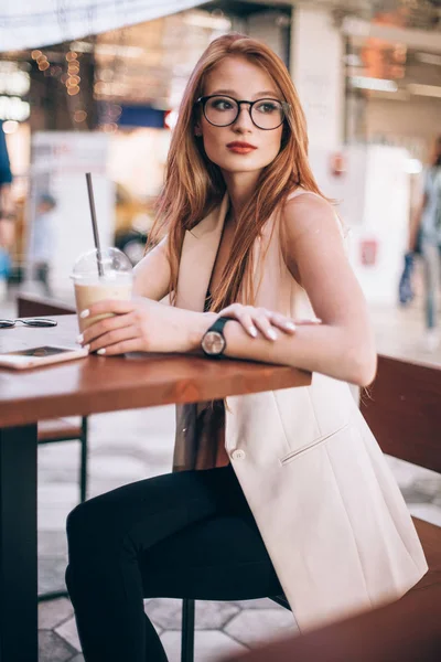 Bir kafede oturan Kızıl saçlı kız. Sütlü kahve içme.