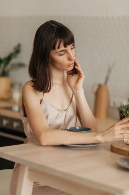 Mutfakta pijamalarıyla gülümseyen bir kız. Güneşli sabahla tanışır. Lezzetli kahve hazırlar.