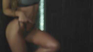 Islak saçlı güzel seksi sarışın kız. Duş su damlaları altında mayoyla poz. Ağır çekim