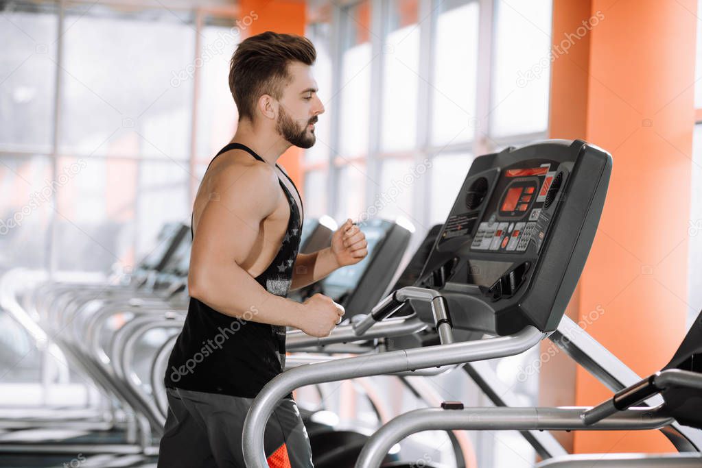 handsome pumped man runs on a treadmill in the gym