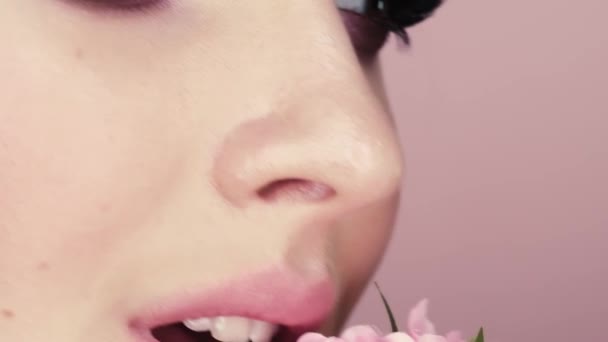 化粧と花を持つ美しい少女の美しさの肖像画 マクロ ピンクの背景のスタジオで撮影 — ストック動画