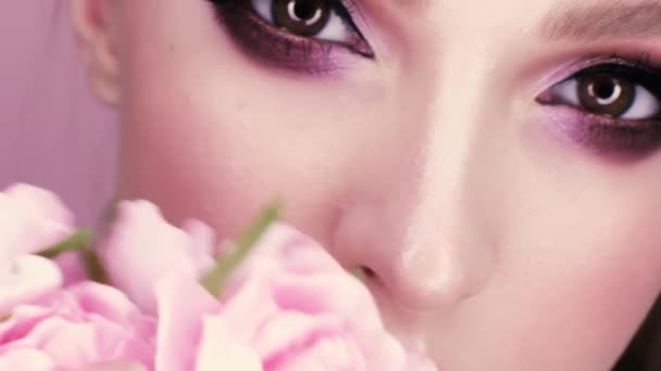 化粧と花を持つ美しい少女の美しさの肖像画 マクロ ピンクの背景のスタジオで撮影 — ストック動画