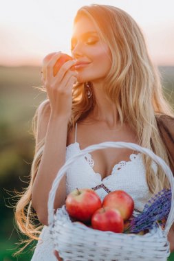 Beyaz elbise güzel seksi sarışın kız meyve sepeti ile günbatımı bir alanda poz 