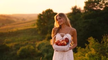 Beyaz elbise güzel seksi sarışın kız meyve sepeti ile günbatımı bir alanda poz 