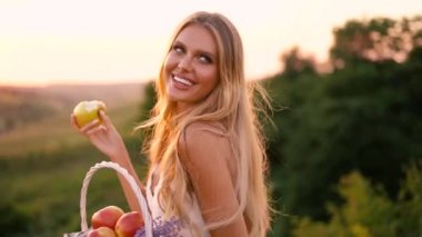 Beyaz elbise güzel seksi sarışın kız meyve sepeti ile günbatımı bir alanda poz 