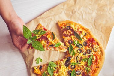 Dilim pizza alarak eller. Dilim pizza tutan el. Pizza dilimleri Beyaz ahşap arka plan alarak el