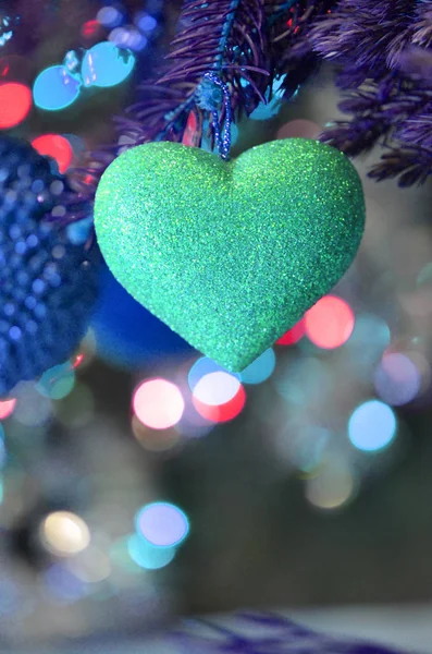 Fir tree branch with blue heart  decoration. Blue heart hanging on Christmas tree branch