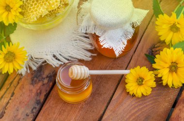 Bal kavanoz ve ahşap sopa yeşil arka plan karşı masada 