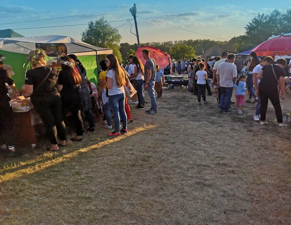 Lidé přicházejí na festival, turisté nakupují na pánech lidového umění — Stock fotografie