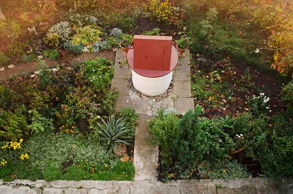 Garden landscape design. Stone well with drinking water in fall garden.