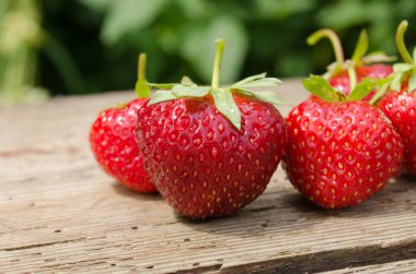 Ahşap masada çilekler ve tarlalar. Doğa tarımına dönelim.