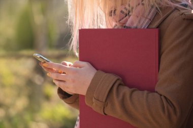 Açık havada kitap okuyan bir öğrenci. Kitapları açık havada olan sevimli sarışın kız. Pembe saçlı kadın elinde kırmızı kitapla 