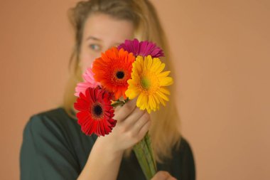 Bir buket papatya çiçeğiyle poz veren genç ve güzel bir kadın. Güzel, çekici bir bayan papatya çiçeğiyle dikiliyor..
