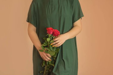 Katı, mütevazı, uzun yeşil elbiseli, kırmızı güllü güzel bir kız. Kırmızı güllerle dolu bir buket kız