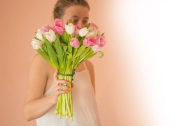 Uzun sarı saçlı, lale buketi tutan mutlu bir kadın.