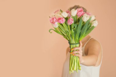 Bej arka planda bir buket çiçekli çekici mutlu kız.