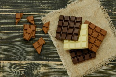 Siyah, süt ve beyaz, çikolata fabrikasının arka planında. Lezzetli çikolata parçaları. Farklı karışık çikolatalar..