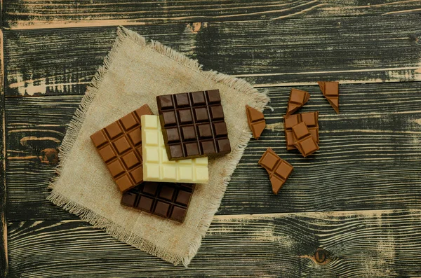 チョコレートバーのグループ別の色 さまざまな種類のお菓子 素朴な木の背景にチョコレートの盛り合わせ — ストック写真