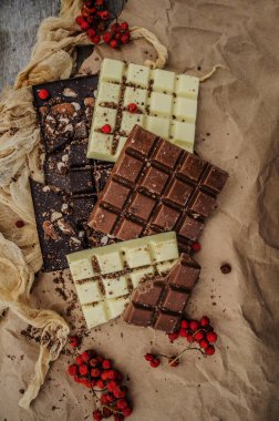  Ahşap arka planda koyu, sütlü ve beyaz çikolatalar..