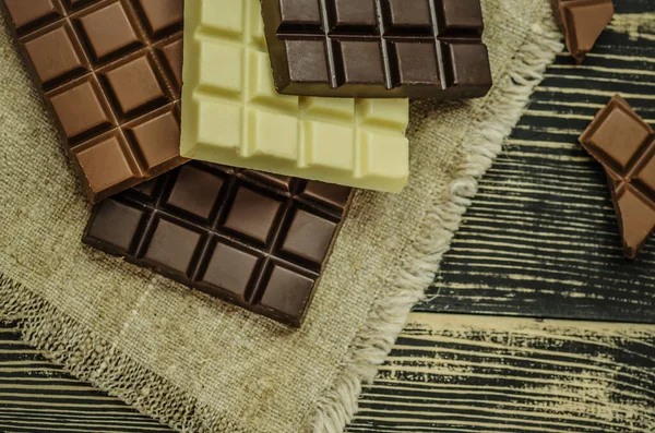 チョコレートバーのグループ別の色 さまざまな種類のお菓子 素朴な木の背景にチョコレートの盛り合わせ — ストック写真