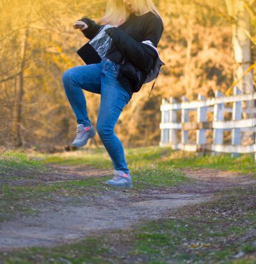 Bahar manzarasında dans eden güzel bir kadın. Renkli bahar parkında sarışın dansçı.