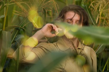 Cheerful young woman elegantly dressed in a golden dress on a corn fiel