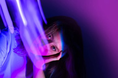 Cheerful young woman in neon electric glow backdrop. Pretty happy woman with bright fluorescent illumination photographic effect.
