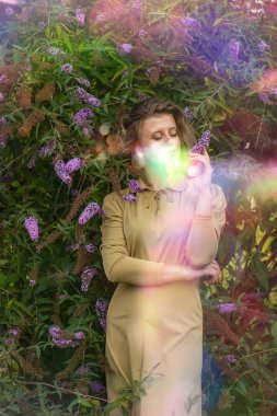 Cheerful caucasian woman with beautiful smile near the buddleia flowers. Concept of fun outdoors.