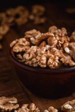 Kırsal ahşap arka planda kahverengi bir kasede taze ceviz çekirdekleri. Ceviz çekirdekleri kapanır.