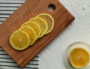 Çizgili bir peçetede tahta üzerinde taze dilimlenmiş limon dilimleri. Vitamin çayı için dilimlenmiş limon. Beyaz arka planda dilimlenmiş limon.
