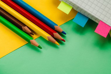 Renkli ahşap kalemler, metin, tasarım veya yaratıcı projeler için boş kopya alanı olan parlak sarı bir arkaplanda düzgün bir şekilde düzenlenmiştir..