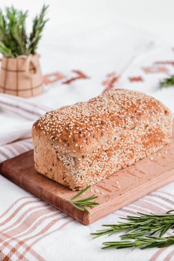 Tahtaya susam tohumu ve biberiye serpiştirilmiş taze ekmek. Masa örtüsü üzerinde sağlıklı ekmek..